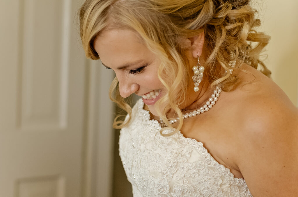 blushing bride blonde lady in sleeveless gown smiling with pearl necklace during destination wedding